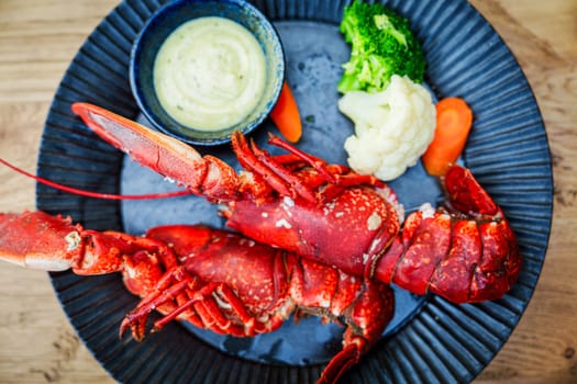 Gourmet red lobster halves plated on an elegant black dish in a fine dining restaurant, showcasing a delectable seafood dish with a luxurious presentation.
