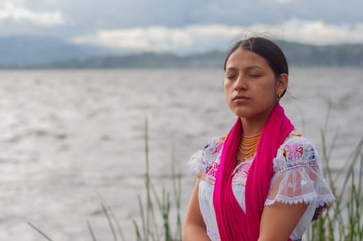 copy space of a beautiful indigenous woman with her eyes closed, traditional indigenous clothing and a fuchsia-colored fabric. High quality photo