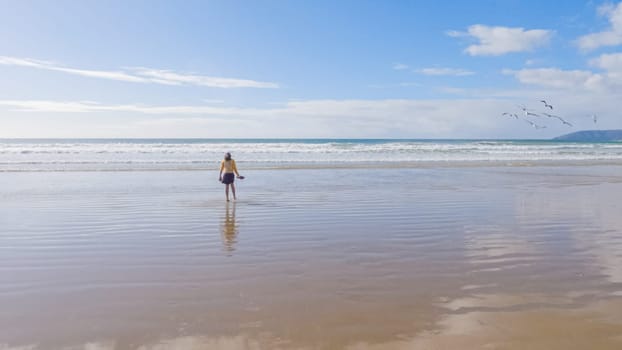 Little girl, braving the cold, joyfully runs in her swimsuit across the beach during winter.