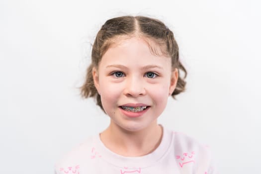 Little girl with rainbow braces smiling at the camera.