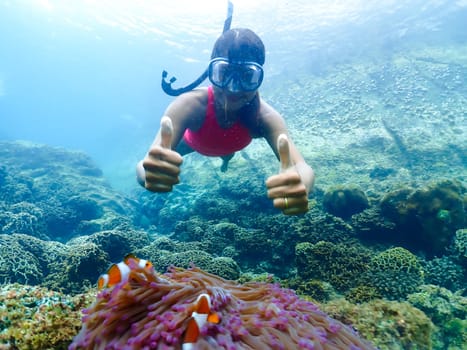Asian woman on a snorkeling trip at Samaesan Thailand. dive underwater with Nemo fishes in the coral reef sea pool. swim activity on a summer beach holiday in Thailand