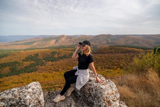 woman on mountain peak looking in beautiful mountain valley in autumn. Landscape with sporty young woman, blu sky in fall. Hiking. Nature.
