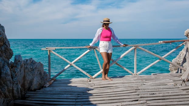 Asian woman on a day trip to Ko Kham Island Sattahip Chonburi Samaesan Thailand a tropical Island in Thailand with a blue ocean, woman at the beach of a tropical island with a wooden pier