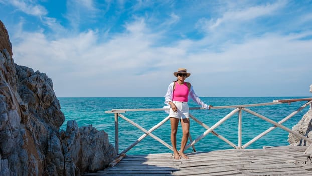 Asian woman on a day trip to Ko Kham Island Sattahip Chonburi Samaesan Thailand a tropical Island in Thailand with a blue ocean, woman at the beach of a tropical island standing at a wooden jetty