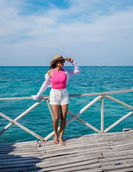 Asian woman on a day trip to Ko Kham Island Sattahip Chonburi Samaesan Thailand a tropical Island in Thailand with a blue ocean, woman at the beach of a tropical island standing at a wooden pier