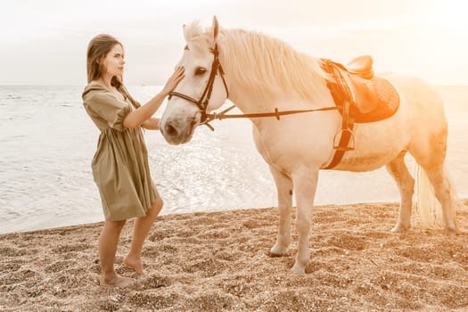 A woman in a dress stands next to a white horse on a beach, with the blue sky and sea in the background