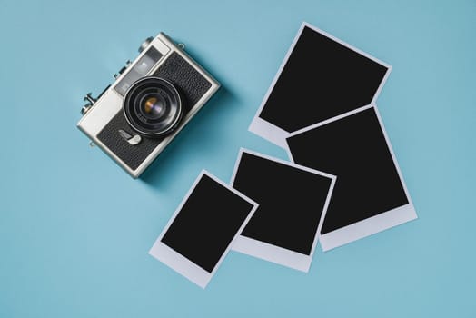 Vintage photo camera and empty photo frames on blue background. Travel moment concept