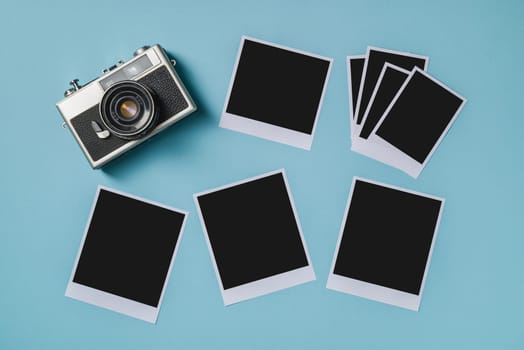 Vintage photo camera and empty photo frames on blue background. Travel moment concept