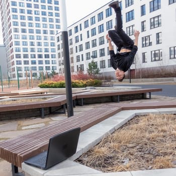 A man types on a laptop outdoors and then does a somersault