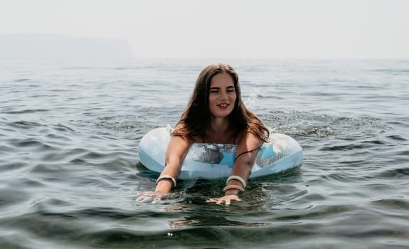 Woman summer sea. Happy woman swimming with inflatable donut on the beach in summer sunny day, surrounded by volcanic mountains. Summer vacation concept