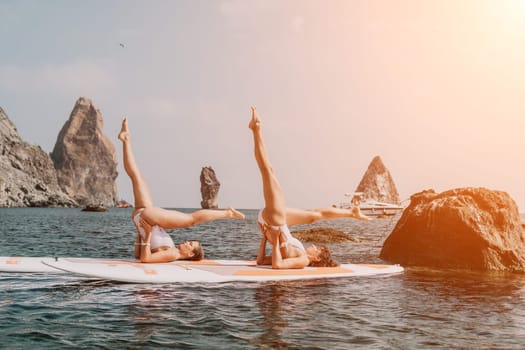 Woman sup yoga. Middle age sporty woman practising yoga pilates on paddle sup surfboard. Female stretching doing workout on sea water. Modern individual hipster outdoor summer sport activity