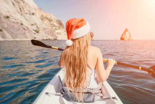 Woman in kayak back view. Happy young woman with long hair floating in transparent kayak on the crystal clear sea. Summer holiday vacation and cheerful female people relaxing having fun on the boat