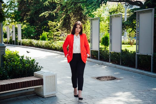 Beautiful fashionable woman in red business suit outdoors