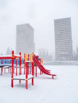 Children's play ground in snow with high-rise buildings on the background. Winter season in British Columbia, Canada.