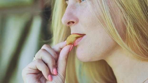 Blonde girl eating chips on the street
