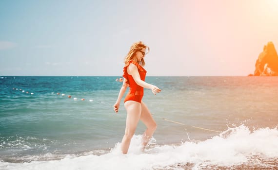 Young happy woman walks carefree on the seaside. Happy lady in red bikini. Portrait beautiful young woman relax smile around beach sea ocean in holiday vacation travel trip.