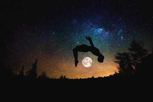 sporty man jumping silhouette at the night starry sky and moon background. Mixed media