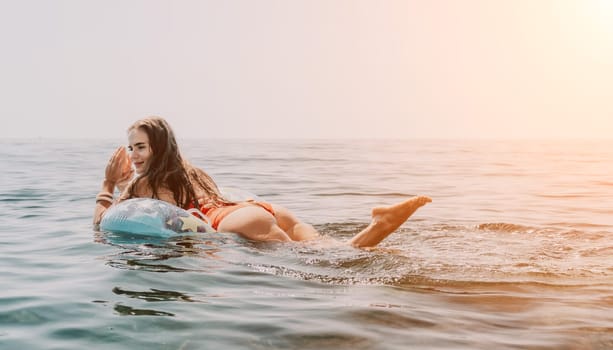 Woman summer sea. Happy woman swimming with inflatable donut on the beach in summer sunny day, surrounded by volcanic mountains. Summer vacation concept