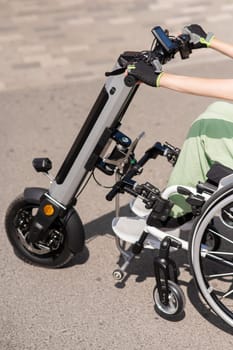 A woman controls a wheelchair using a special manual device. Close up an electric handbike