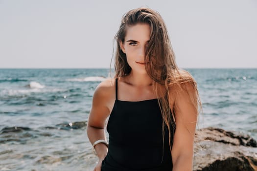 Woman travel sea. Young Happy woman in a long red dress posing on a beach near the sea on background of volcanic rocks, like in Iceland, sharing travel adventure journey