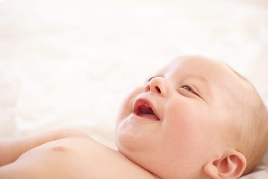 Baby, smile on bed and funny laugh of young child in development, innocent and relax at home. Happy kid, excited infant in nursery and rest in bedroom, healthy body and cute, adorable or mockup space.