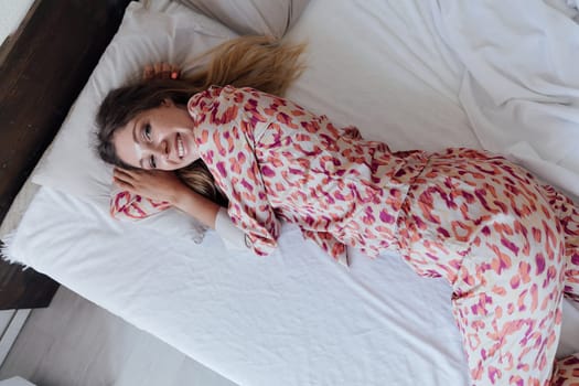 slender woman in pajamas in bedroom on bed