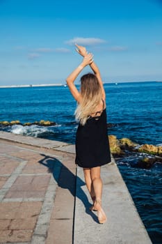 slender woman in black summer dress on the seashore