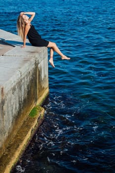 slender woman in black summer dress on the seashore