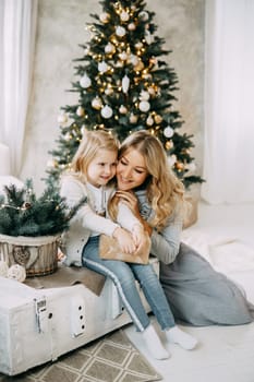 Happy family: mother and daughter. Family in a bright New Year's interior with a Christmas tree