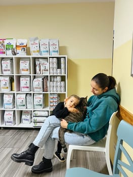 Little girl with her mother sitting with a cat in a veterinary clinic. High quality photo