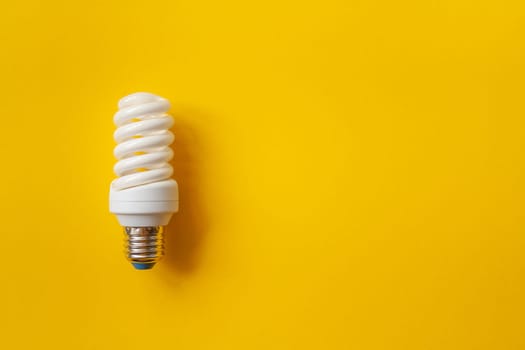 Energy saving light bulb on a orange background. Economical consumption of electricity. The concept of nature conservation with place for text