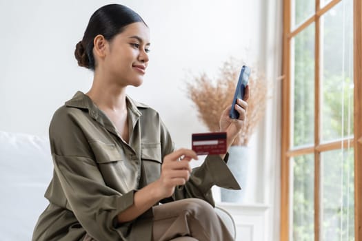 Young happy Asian woman buy product by online shopping at home while ordering items from the internet with credit card online payment protected by uttermost cyber security from online store platform