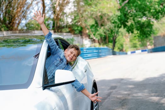 Excited and happy young little boy with smile on his face show up on car window while driving, playful and cheerful expression while on the road trip traveling by car during summertime. Perpetual