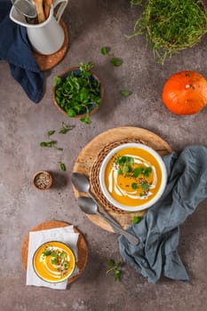 Delicious homemade creamy pumpkin soup with cream with sesame seeds and watercress.