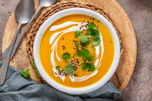 Delicious homemade creamy pumpkin soup with cream with sesame seeds and watercress.