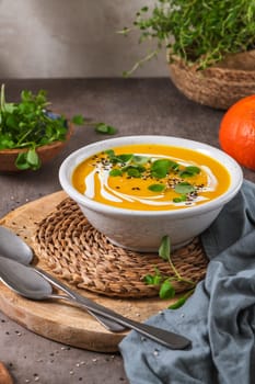 Delicious homemade creamy pumpkin soup with cream with sesame seeds and watercress.