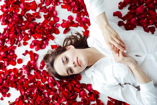 Woman lying in rose petals indoors red