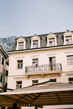 Carved attic on an ancient stone house with a wrought-iron balcony at the foot of the mountains. High quality photo