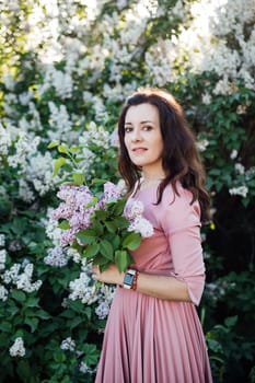 Beautiful woman with a bouquet of lilacs on a walk nature flowers