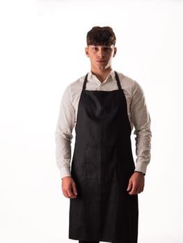 Young chef or waiter posing, wearing black apron and white shirt isolated on white background