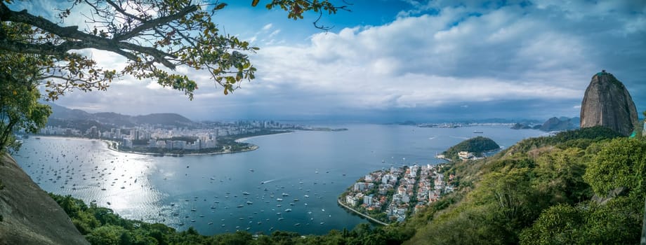 Breathtaking aerial view of Botafogo Bay, featuring sailboats, Sugarloaf Mountain, and Niteroi Bridge in Rio de Janeiro.