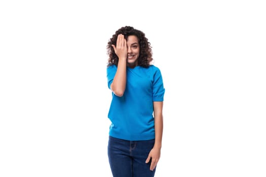 corporate clothing concept. young slender curly woman with black hair dressed in a blue t-shirt with mockup.
