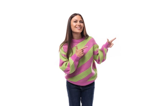 stylish cheerful young brunette woman in a striped pink blouse points fingers at the space for advertising on a white background with copy space.