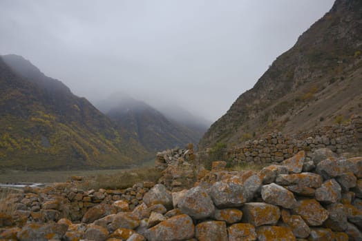 Cloudy foggy sky, mountain peaks covered with fog in the morning. Caucasus Mountains, Upper Balkaria, Russia