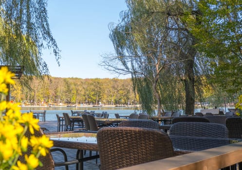 Recreation area in the city park. Outdoor tables and benches by the lake for relaxing and eating.