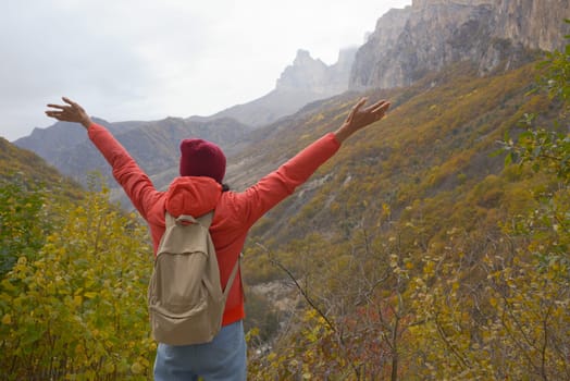 Woman outdoors exploring the Caucasus Mountains in Russia, travel, lifestyle, hiking, girl traveler raised her hands, active autumn holidays, hiking.