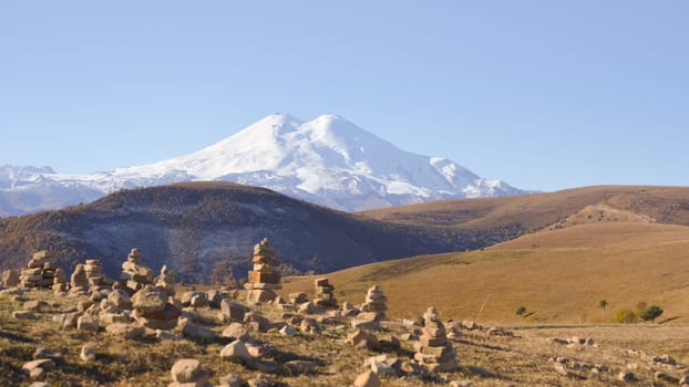 The Garden of Stones with Mount Elbrus as a backdrop. Pyramids of stones. Pebble tower balance harmony stones arrangement. Spa therapy summer travel vacation.