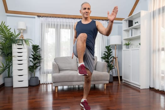 Athletic and sporty senior man make running pose at home. Healthy fit body lifestyle as home workout exercise concept after retirement. Clout