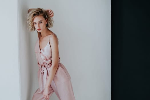 portrait of a beautiful fashionable woman in a pink jumpsuit against a black background