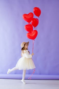 little girl with red balloons in the shape of a heart